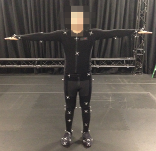 Photo of an actor in a MoCap suit with markers placed, standing in a T-Pose.
